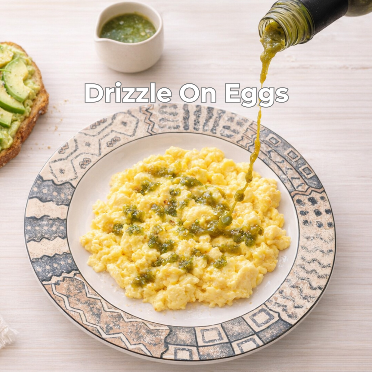 Scrambled eggs on a decorative plate with a drizzle of green super mirchi sauce, accompanied by toast with avocado.