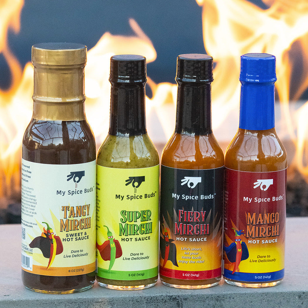 Four bottles of 'My Spice Buds' hot sauces with colorful labels against a fiery background.