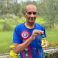 Man in blue shirt with rosette holding a bottle outdoors