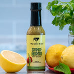 Bottle of My Spice Buds Super Mirchi Hot Sauce with lemons and herbs on a blurred background 21