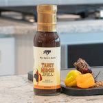 Bottle of My Spice Buds Tangy Mirch sauce on a kitchen counter with peppers. 20