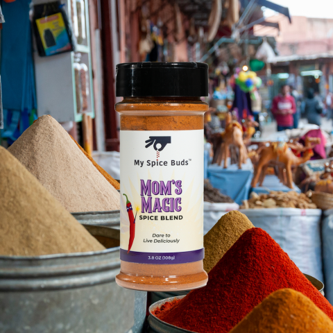 Spice blend jar labeled 'Mom's Magic' by My Spice Buds with a market background